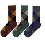 Three pairs of argyle patterned socks in brown, green, and blue on a white background.